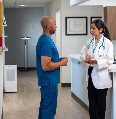 two doctors talking in the office next to an air purifier