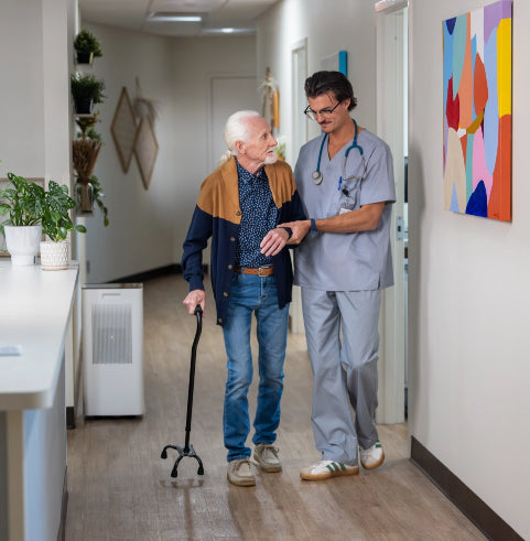a physician helping to walk a patient in a clinic next to an air purifier.