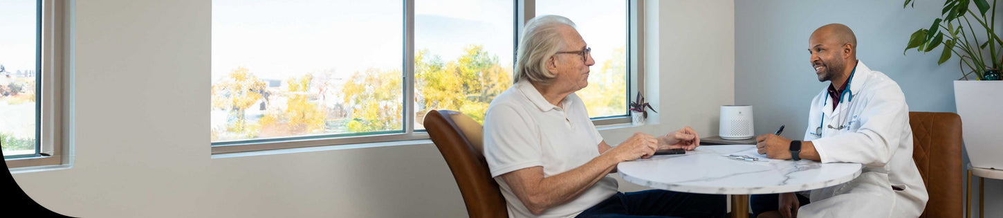 a doctor talking to a long term care resident with an air purifier in the background