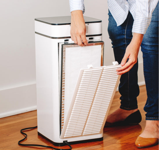 a person changing an air filter in an air purifier