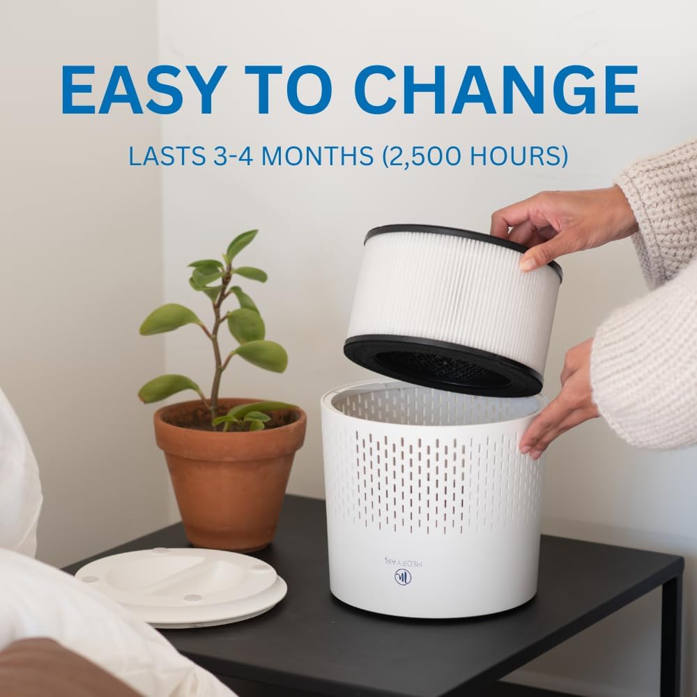 a bedroom with a nightstand holding a plant and a MA 12 Pro air purifier featuring a HEPA filter with words reading easy to change lasts 3-4 months (2,500 hours)